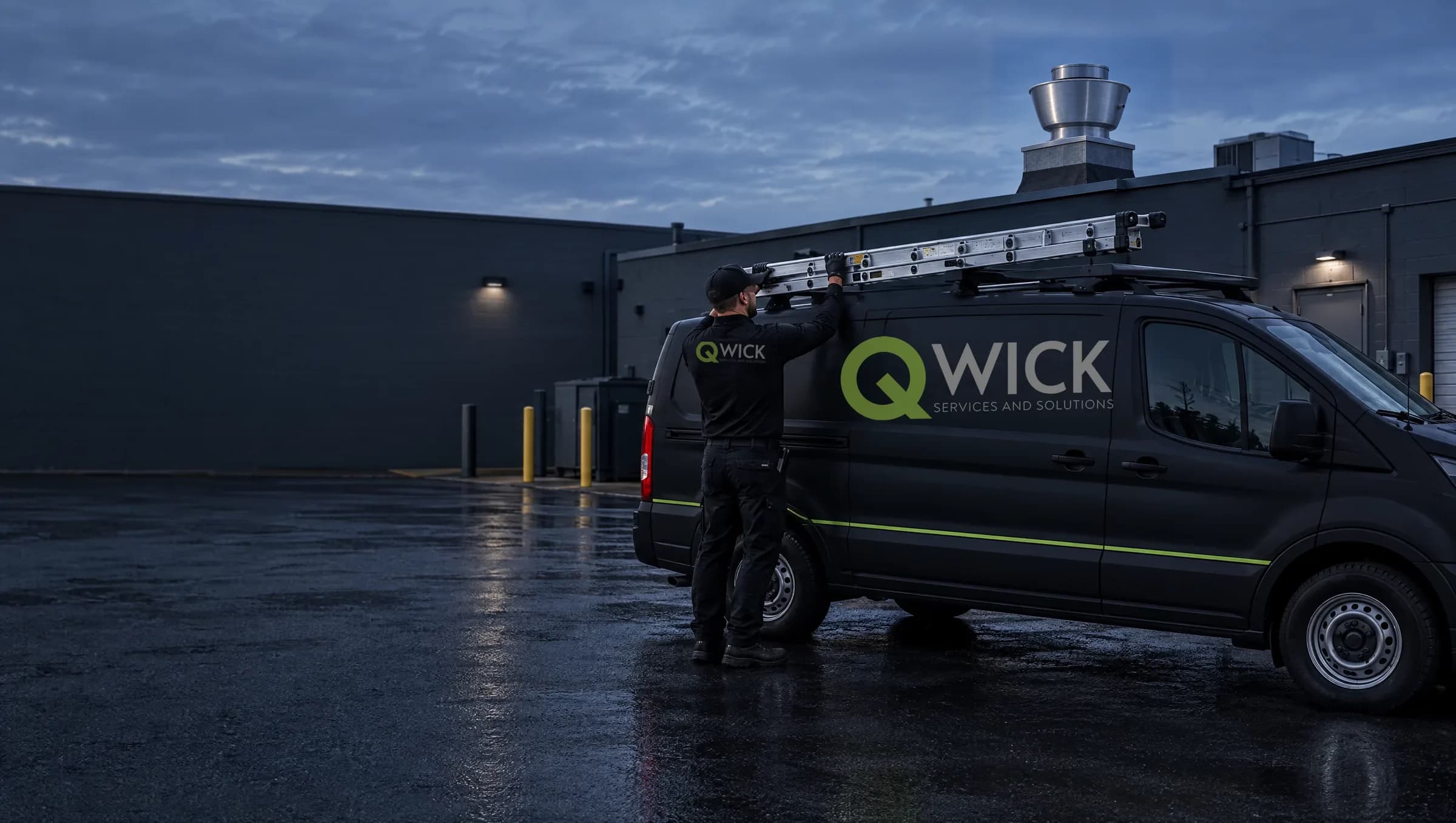 Qwick Services And Solutions technician unloading a ladder from a branded service van outside a commercial kitchen at dusk