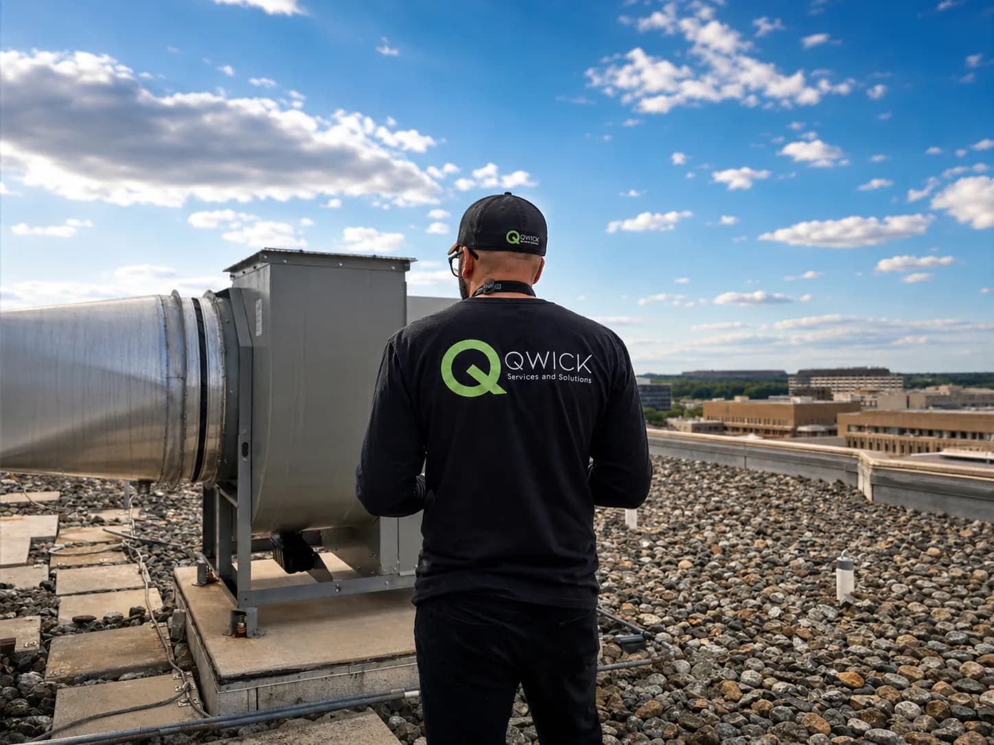 Qwick Services And Solutions technician servicing a rooftop commercial kitchen exhaust fan